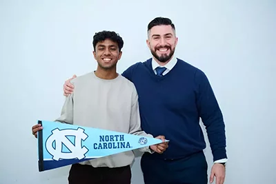 Student holding up his North Carolina University banner with his tutor Aydin from Olympus College Prep